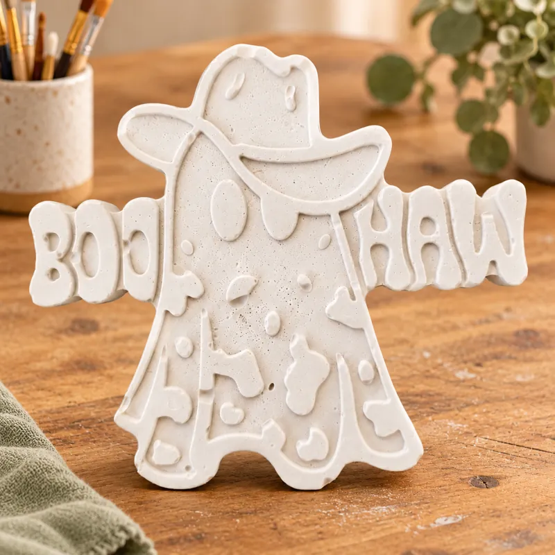 Unpainted Boo Haw Ghost plaster figure on a craft table