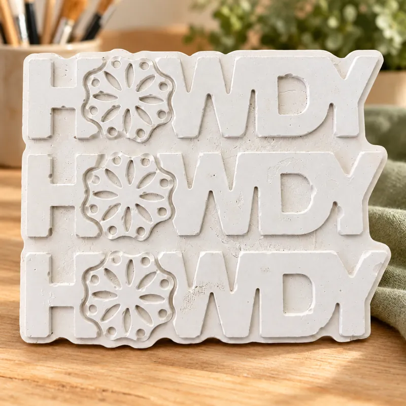 Unpainted Howdy Bloom Sign plaster figure on a craft table